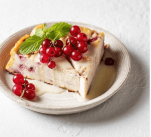 A creamy and delicious slice of healthy cheesecake topped with fresh berries and a light drizzle of honey, served on a white plate.