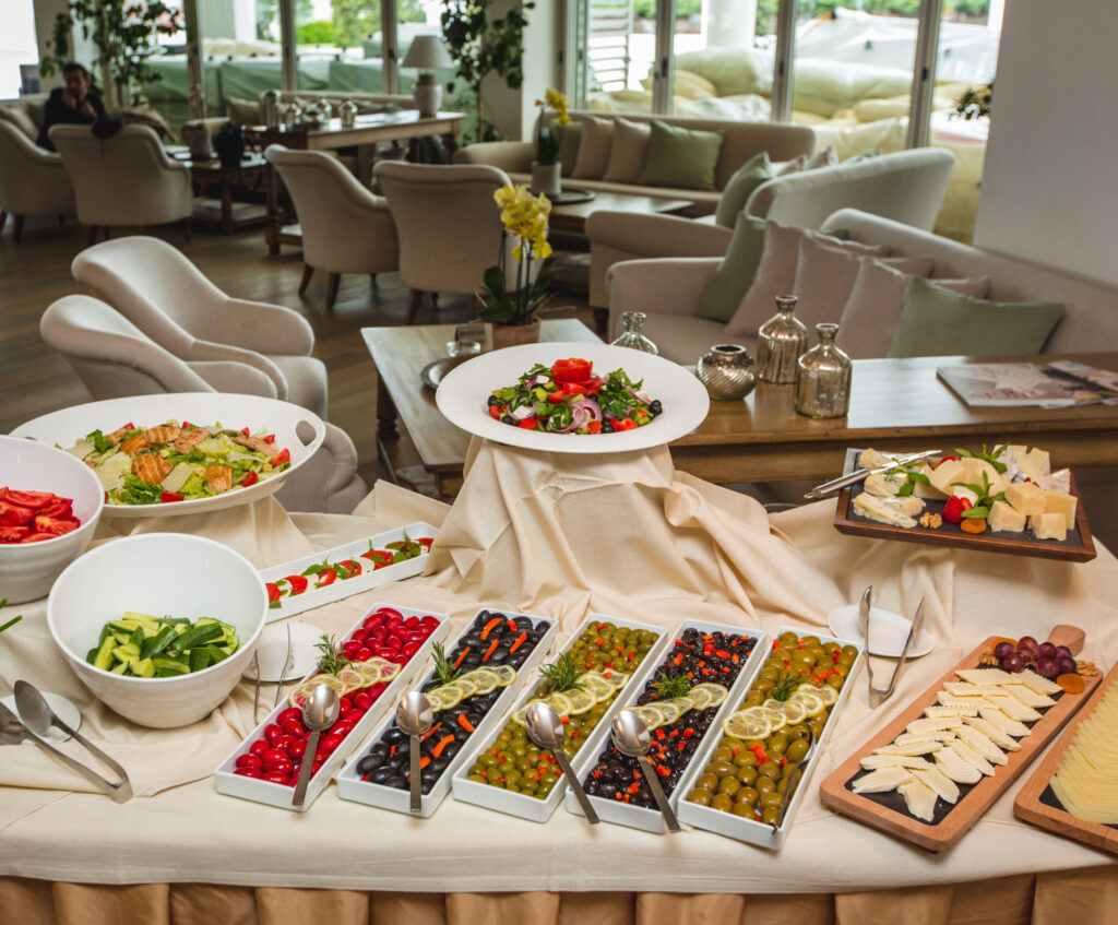 "Buffet table with fresh salads, assorted olives, cheeses, and vegetables in a modern, cozy dining area."