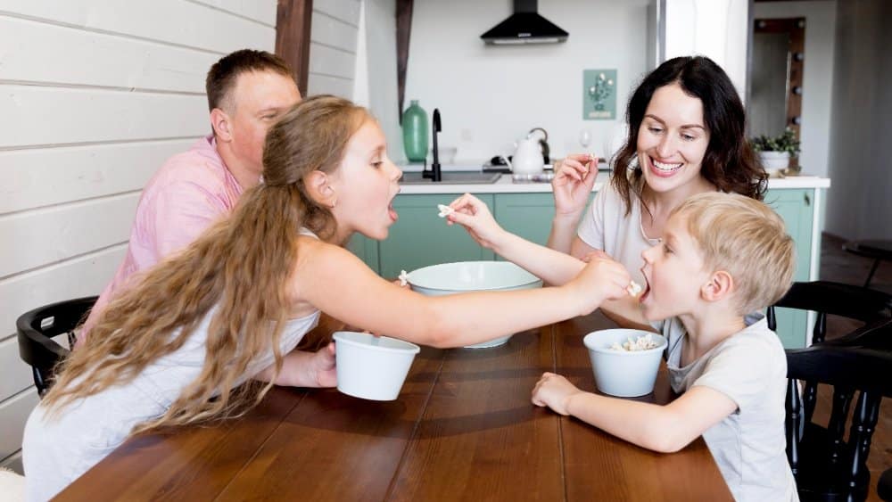 Family enjoying a healthy meal together at a dining table in a modern kitchen.