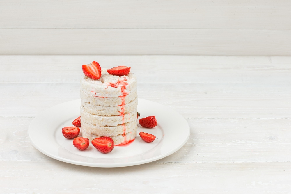 Keto cheesecake bites stacked and garnished with fresh strawberries on a white plate