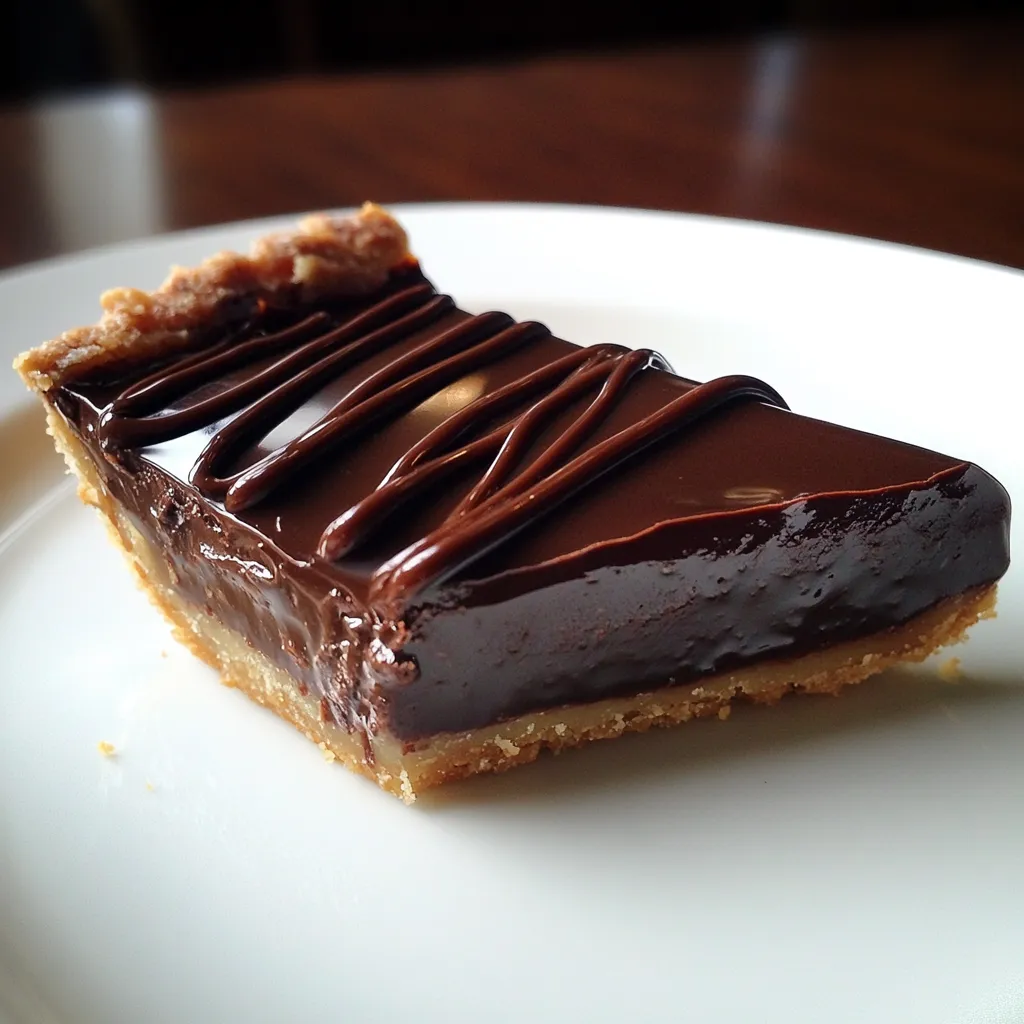 A rich and silky slice of Decadent Chocolate Ganache Tart with a crisp crust and glossy chocolate drizzle, served on a white plate.