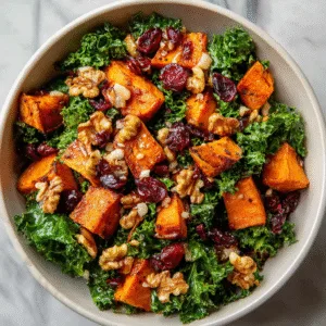 Roasted sweet potato and kale salad with dried cranberries, walnuts, and crumbled goat cheese in rustic bowl